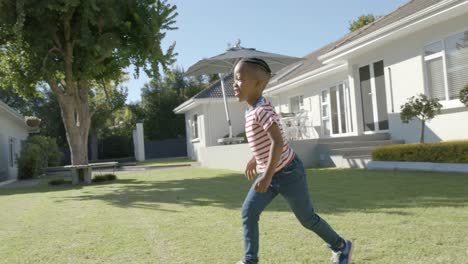 Fröhlicher-Afroamerikanischer-Junge,-Der-Im-Sonnigen-Garten-Spielt-Und-Rennt,-In-Zeitlupe