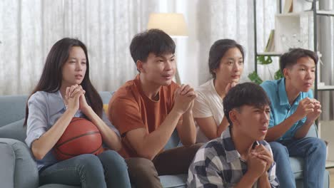 아시아 십대 들 이 집 에서 tv 에서 농구 경기 를 지켜보고 응원 하고 있다