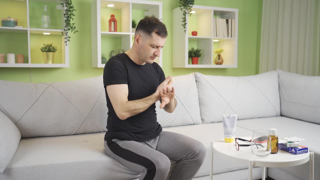 건조한 피부를 가진 남자가 손에 크림을 바르고 있습니다.