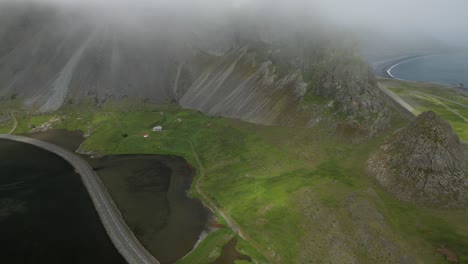 Misty-aerial-view,-coastal-road-near-surreal-steep-mountain