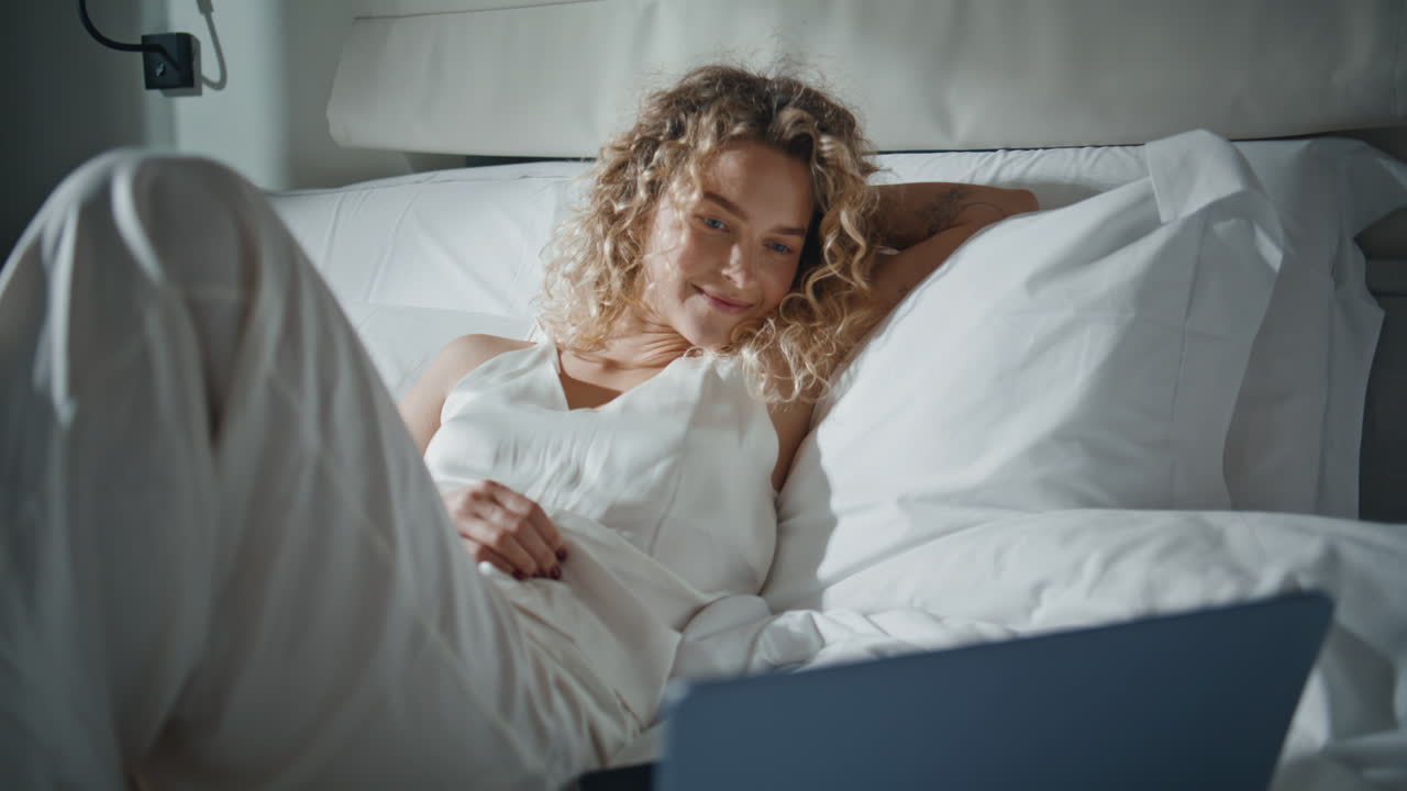 lady watching computer in bed closeup. Relaxed girl laughing at home