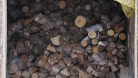 timber firewood stash outside during winter time, snow is falling, shallow depth of field, handheld slowmotion