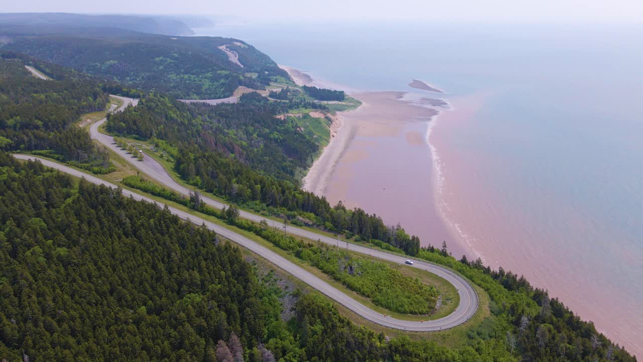 Aerial shot of one of the most famous landscapes in Canada located at the Bay of Fundy trail in New Brunswick where the highway is close by the massive cliffs edge with the beach in the background