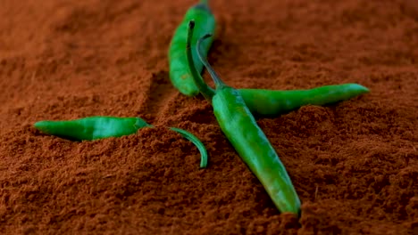 Green-chili-peppers-dropping-on-red-chili-powder-or-paprika-slow-motion-bounce