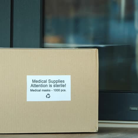 el mensajero trae una caja con máscaras médicas protectoras a la puerta