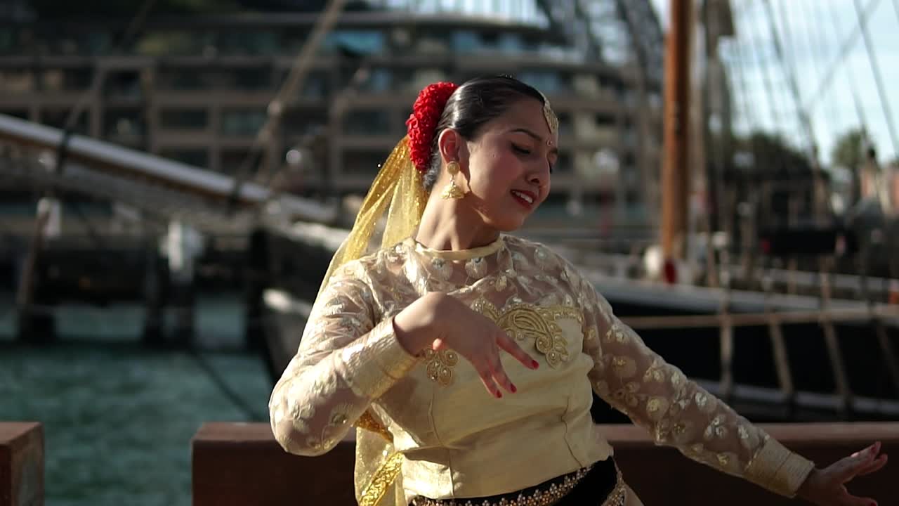 mujer realizando la danza clásica de la india frente al puente del puerto de sídney en australia - toma media