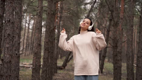 Fröhliche-Schöne-Frau,-Die-Allein-Im-Wald-Tanzt-Und-Musik-Hört-Und-Die-Freiheit-Genießt,-Auf-Die-Kamera-Zuzugehen