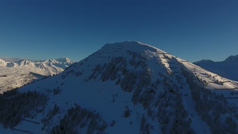 Luftdrohnenaufnahme,-Die-Bei-Sonnenuntergang-über-Einen-Berg-Fliegt.-Verschneite-Landschaft