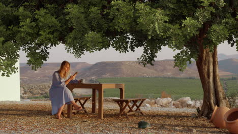 woman villager with phone and tea resting under the tree