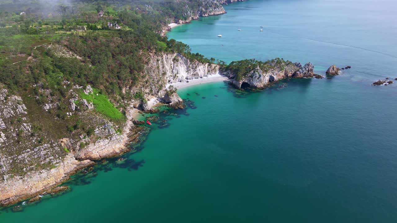 Turquoise bay and Virgin Island beach surrounded by rocky cliffs and pine trees on Crozon Peninsula Brittany, France