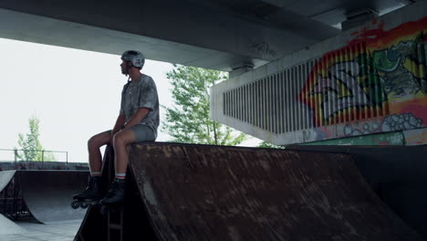 Entspannter-Rollschuhläufer,-Der-Sich-Auf-Der-Rampe-Im-Skatepark-Ausruht.-Gutaussehender-Mann,-Der-Eine-Pause-Macht