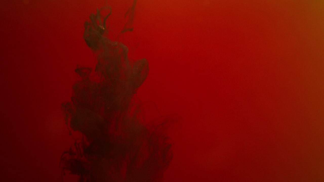 오렌지색과 빨간색 페인트 또는 염료가 색 배경에 물에 떨어지면서 회전하는 다채로운 연기 배경을 만니다.