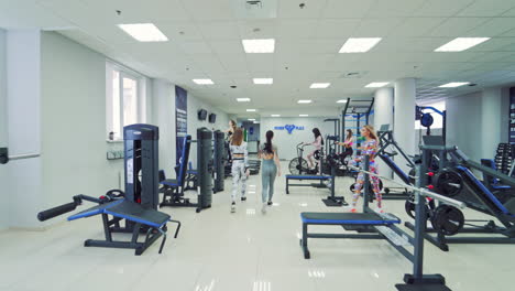 modern fitness center with various simulators. back view of athletic young women going out confidently after training of the health club. camera moves forward.