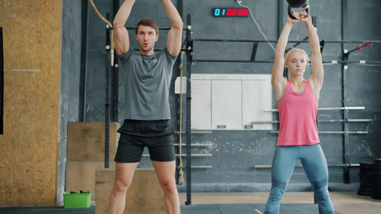 Couple working out with kettlebells in a gym