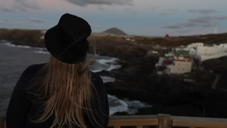 eine junge frau mit hut bewundert die landschaft und die klippen an der küste der gemeinde galdar auf der insel gran canaria und bei sonnenuntergang