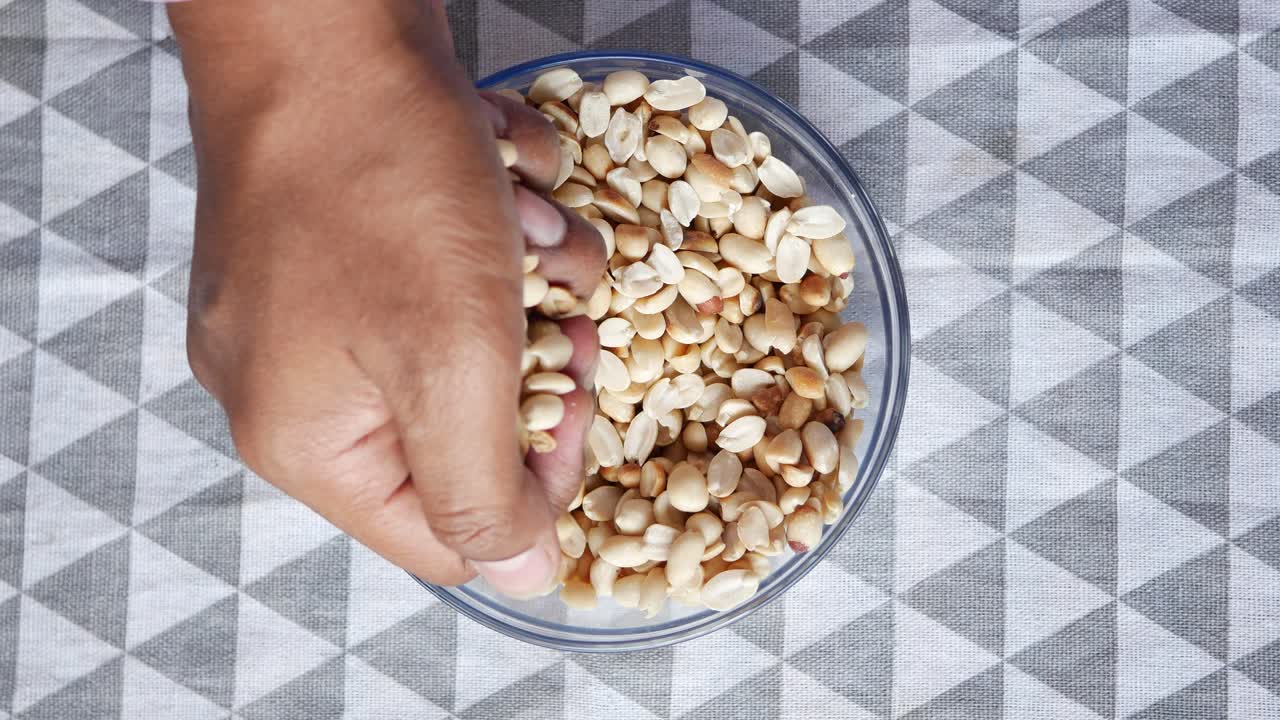 manos mezclando cacahuetes en un cuenco