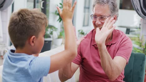 Happy-caucasian-grandfather-and-grandson-sitting-on-sofa-and-using-sign-language,-slow-motion