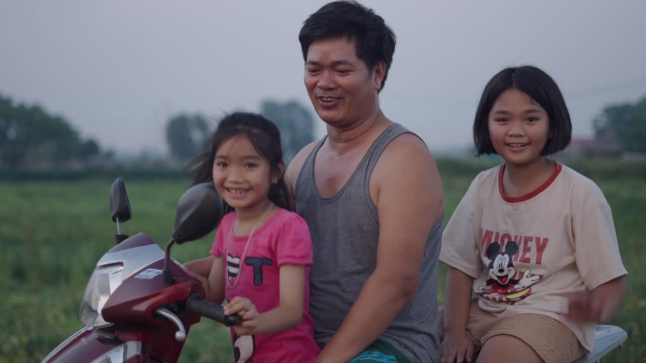 Father and daughters on a motorbike in rural Vietnam