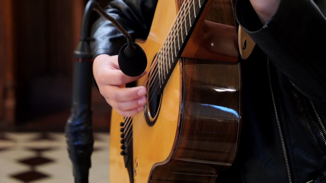 Primo piano della mano di una donna che suona la chitarra acustica a un matrimonio in chiesa.