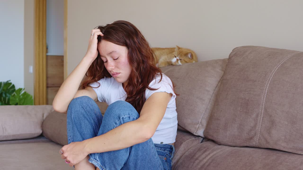 A woman is sitting on a couch looking sad