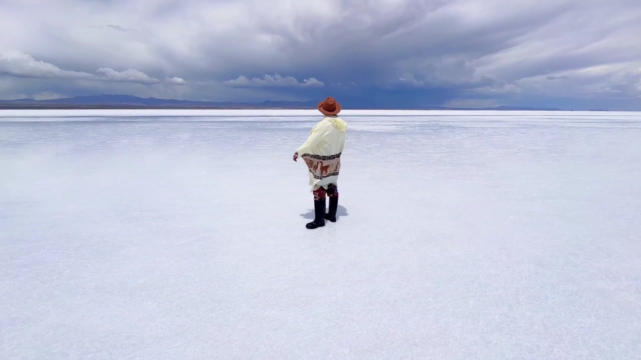 Pria Mengenakan Ponco Tradisional Berdiri di Dataran Garam Salar de Uyuni, Bolivia.