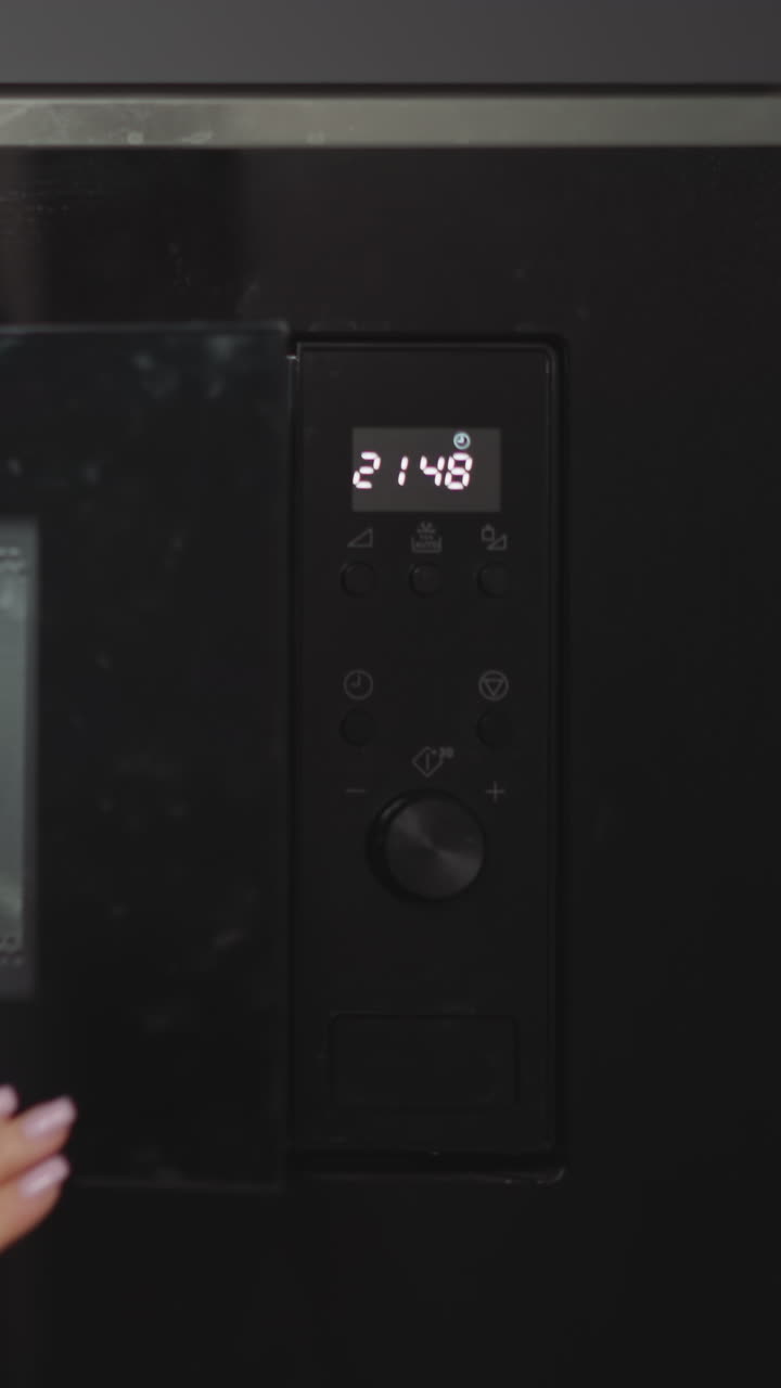 las manos femeninas ponen el plato con el plato en el moderno horno de microondas incorporado. la mujer joven cocina la cena en casa. calentamiento conveniente y rápido de la comida en la cocina