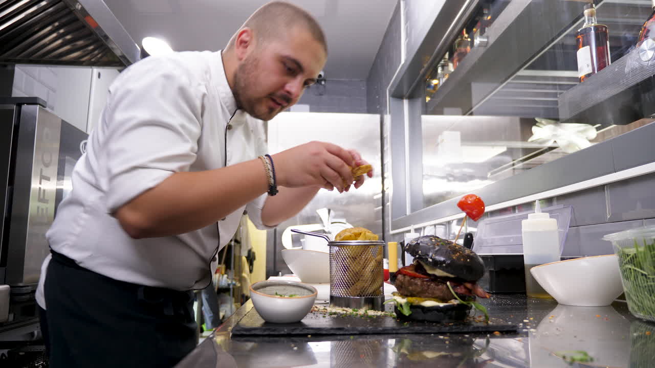 Chef preparing a burger and fries in a restaurant kitchen