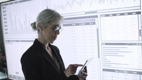 mujer de negocios exitosa escribiendo en tableta y viendo gráficos