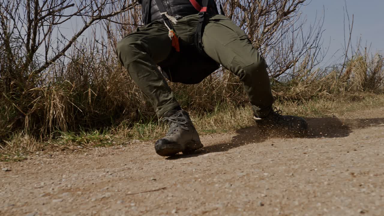 Close-up shot of paragliding enthusiast sliding on dirt, Zoutelande, Netherlands, super slow motion