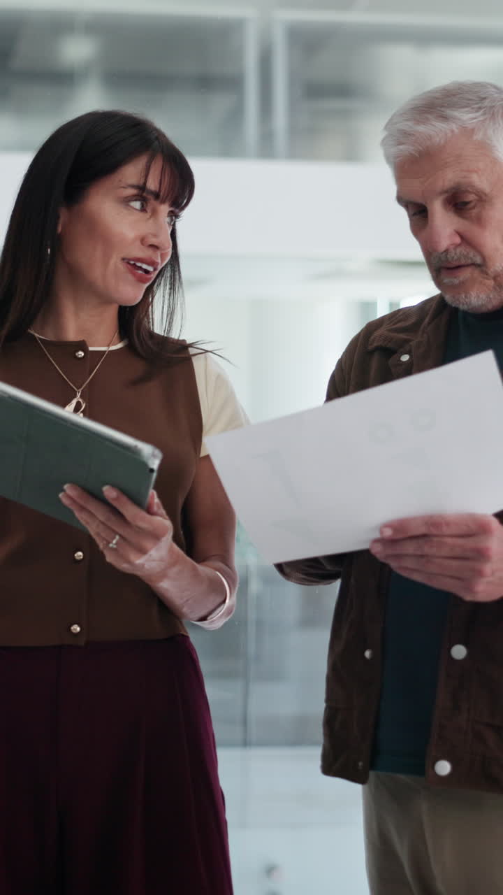 Colegas de Trabalho Discutindo Documentos e Tablet em Escritório Moderno