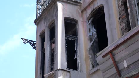 a damaged building with broken windows and a rusty metal balcony