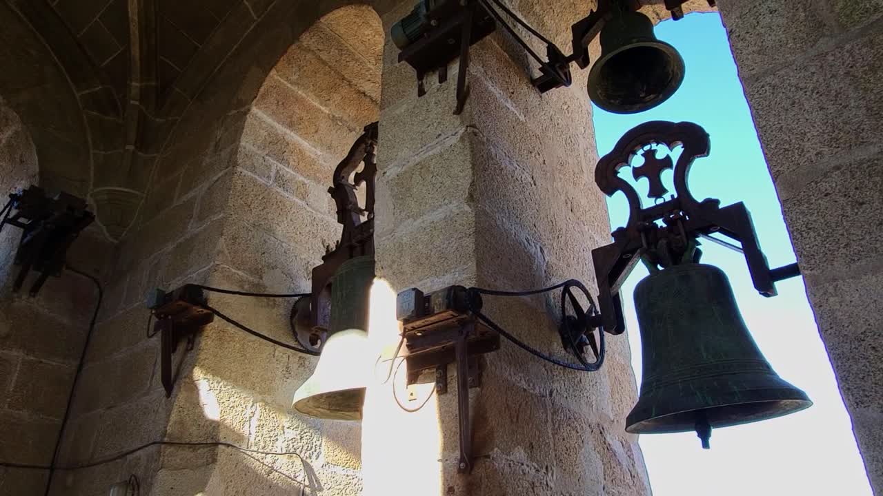 Wrought iron bells installed in a medieval bell tower. Panoramic interior view of an old medieval bell tower. Cáceres. Spain