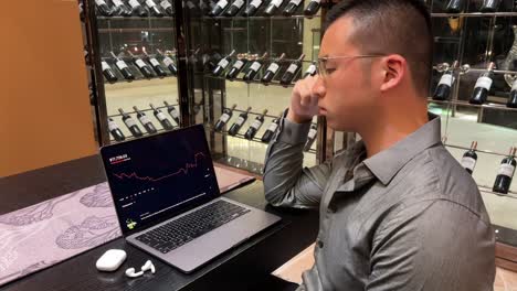 wealthy asian millennial male stressed over stock market loss while checking brokerage account in his luxurious home