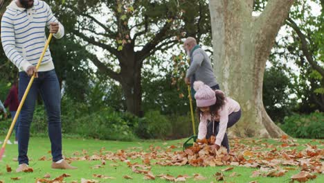 video of happy african american father and daughter collecting leaves with grandfather in garden