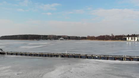 costa del lago de invierno con muelle congelado y cubierta de hielo.
