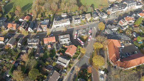 Aerial-of-buses-parked-at-bus-stop-in-a-small-town-in-autumn