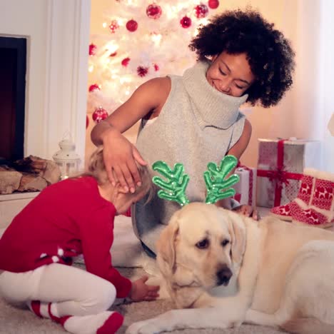 mom and daughter in sweaters play with pet dog