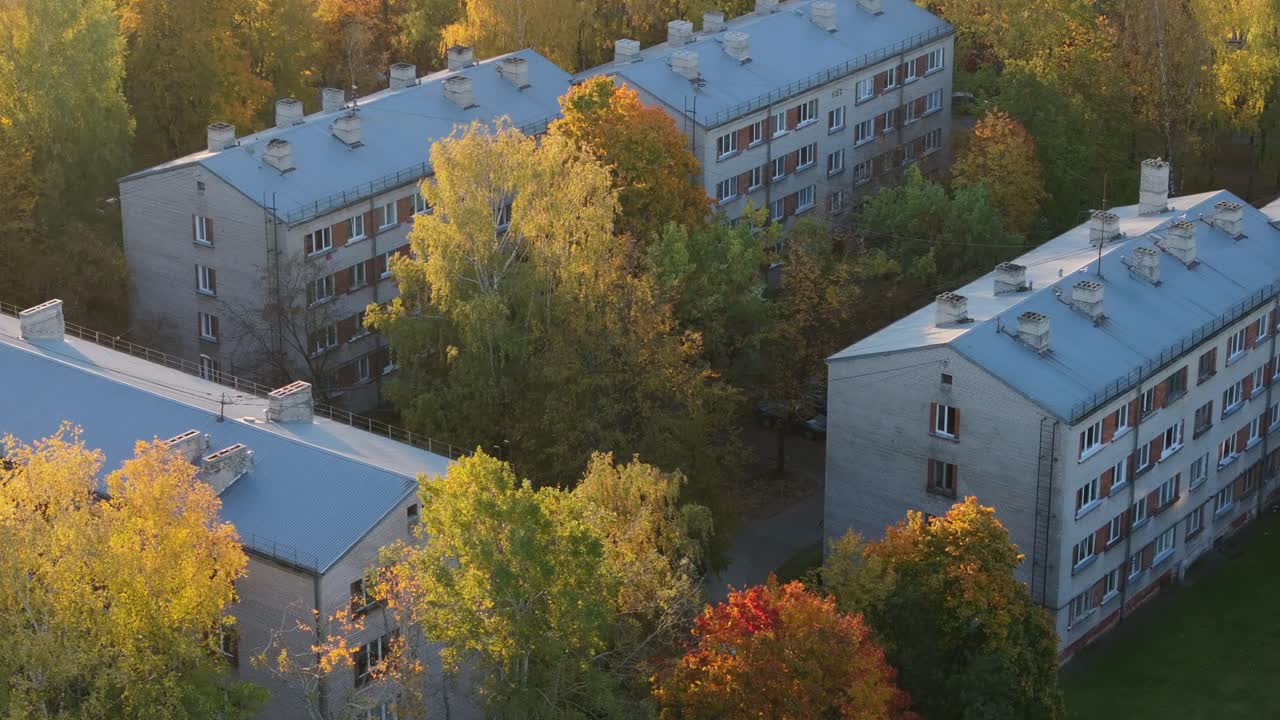 Golden autumn trees surround old Soviet-style apartment buildings in Latvia