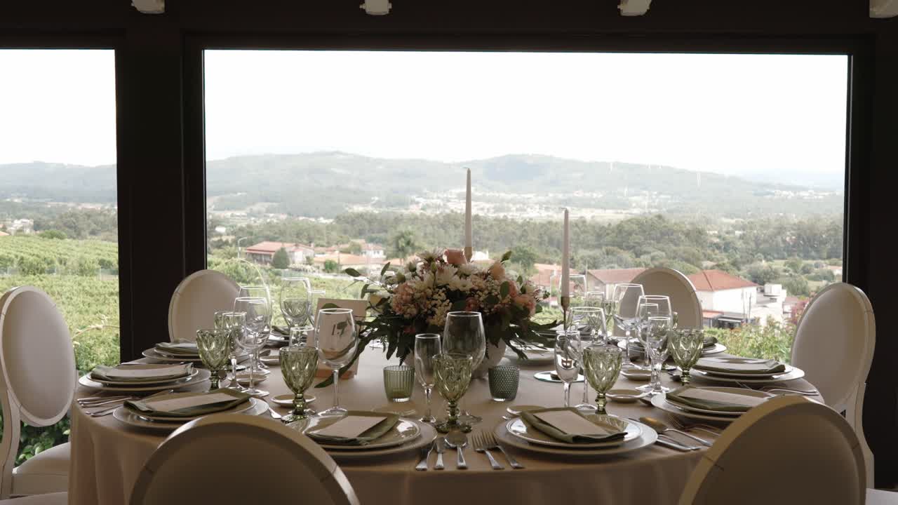 round wedding table set for guests with mountain view through large window in bright daylight