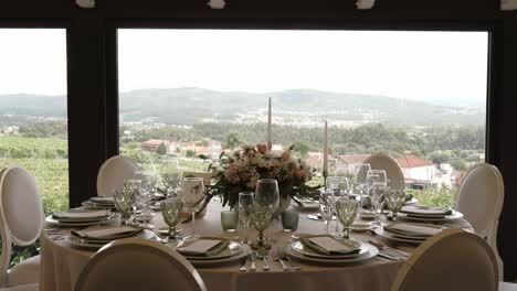 round wedding table set for guests with mountain view through large window in bright daylight