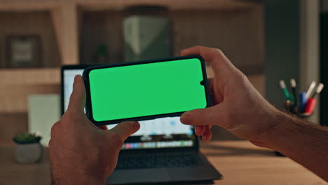 gamer using mockup cellphone in dark home closeup. man watching social media
