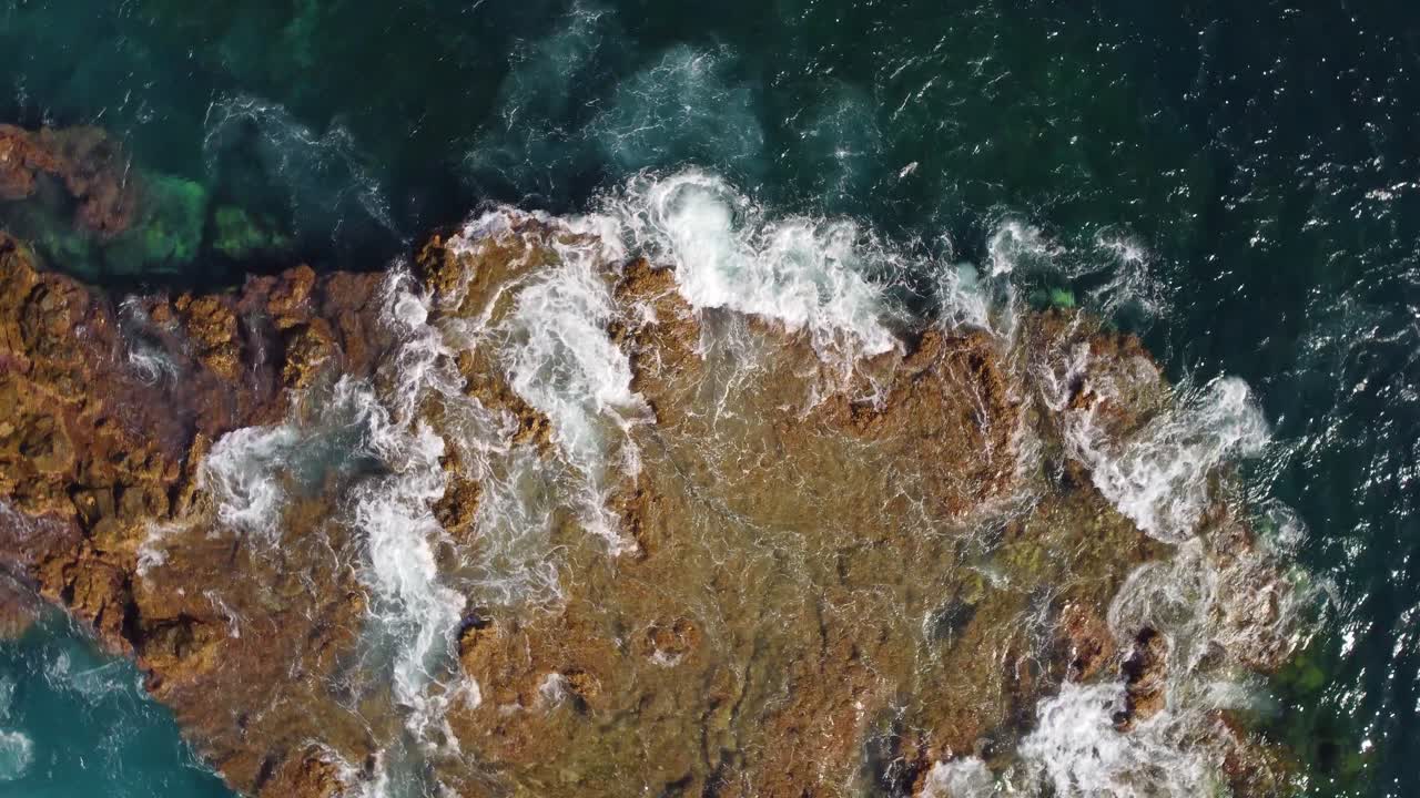 Vista aerea orbitale dall'alto di una costa rocciosa e aspra con affascinante schiuma marina turchese alle Isole Canarie, Spagna.