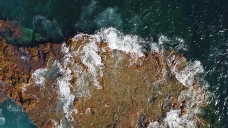 vista aérea en órbita de arriba hacia abajo de la costa rocosa áspera de la hipnotizante espuma marina turquesa en las islas canarias, españa