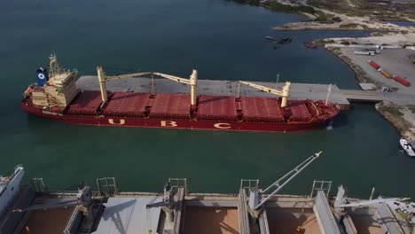 vista aérea de un buque que transporta materia prima, anclado a un muelle comercial