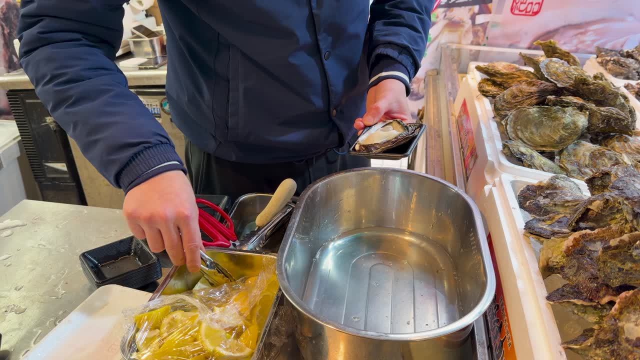 Primo piano di un venditore che apre e guarnisce ostriche fresche in un mercato di Tokyo