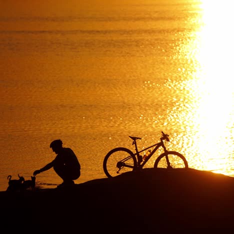 man with bicycle resting on beach