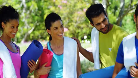 people with rolled exercise mats talking in the park 4k