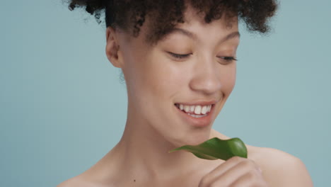 close-up-portrait-sexy-young-woman-touching-face-with-leaf-caressing-smooth-healthy-skin-complexion-enjoying-playful-natural-beauty-on-blue-background-skincare-concept