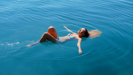 woman floating serene in blue water