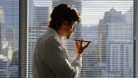 Side-view-of-young-Caucasian-male-executive-talking-on-mobile-phone-near-window-in-modern-office-4k